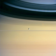 One of Saturn’s moons appears to hover above the planet’s rings.